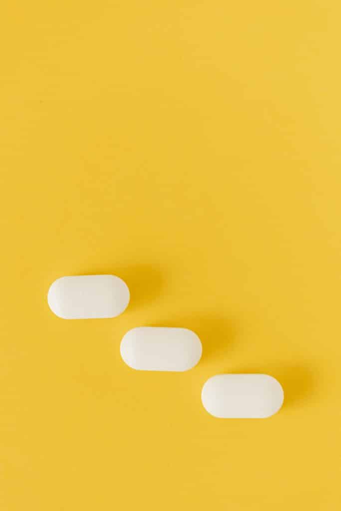Drie witte pillen op een gele achtergrond